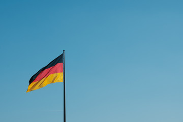 german flag on pole on blue sky background with copy space
