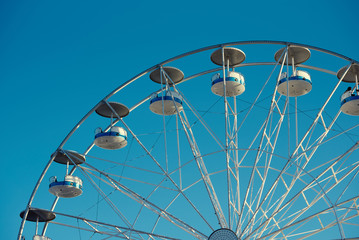 Ferris wheel in the summer evening against blue sky in amusement park.
