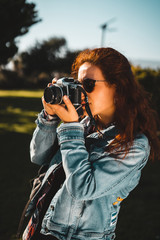 Woman photographer is taking images with retro styled digital photo camera, outdoor and sunlight