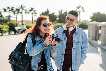 Happy couple of tourists photographing in a park in a sunny day