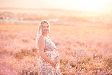 Fototapeta na wymiar Smiling pregnant woman posing in lavender field. Looking at camera. Motherhood. Maternity.