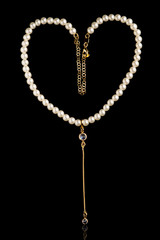 White pearl necklace with gold chain on black background