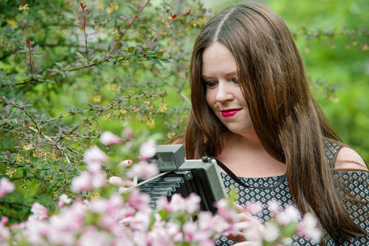 Young woman in the garden taking photos with a vintage camera
