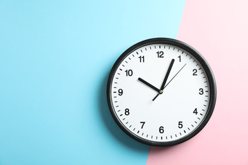 Big beautiful office clock on two tone solid color pink and light blue background