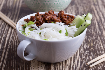 Asian style bowl with ground beef, rice noodles, cucumber, green onions and sesame seeds