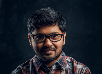 Portrait of a dark skinned chubby guy looking into a camera in a studio on a black background