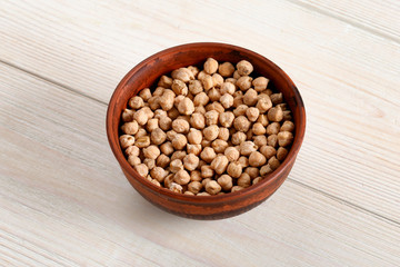 Clay plate with chickpeas on a light wooden table