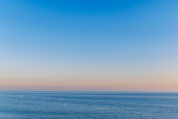 beautiful blue sky over a slightly rippling blue sea in Ramsgate, Kent with the golden haze of a late afternoon sunset hovering above the horizon