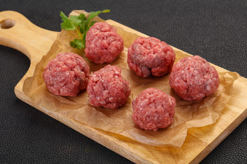 Raw meatball over wooden background