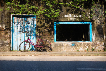 Bicicle in front of a abandoned building with blue door and window, Kochi, Kerala, India