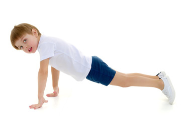 A little boy in a clean white T-shirt is engaged in fitness.