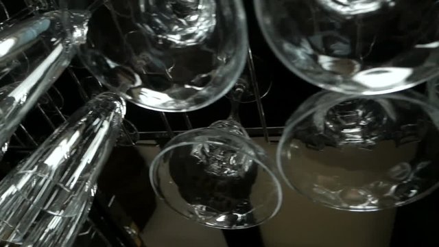 Empty glasses for wine and champagne hanging over a bar rack