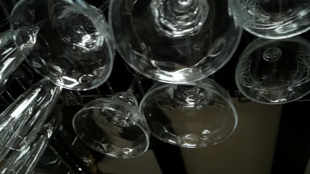 Empty glasses for wine and champagne hanging over a bar rack