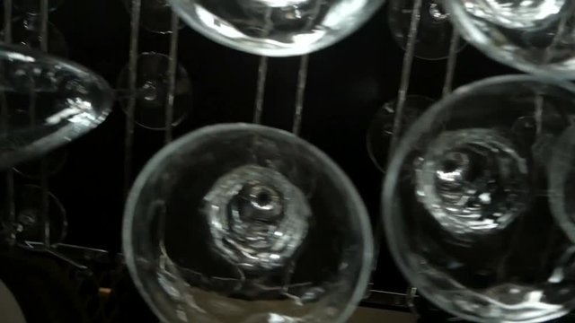 Empty glasses for wine and champagne hanging over a bar rack