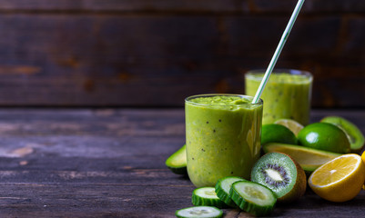 Green smoothie on green background made by avocado, lemon and kiwi.