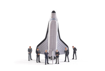 Startup concept. Figures of businessman with space shuttle on white background