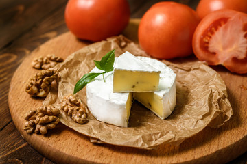 Camembert or Brie cheese with walnut kernels on wooden wooden background. Copy space. white mold grows on top Penicillium camemberti. 