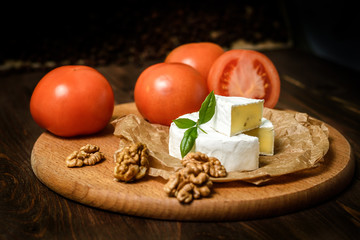Camembert or Brie cheese with walnut kernels on wooden wooden background. Copy space. white mold grows on top Penicillium camemberti. 
