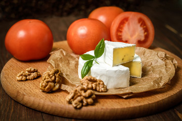 Camembert or Brie cheese with walnut kernels on wooden wooden background. Copy space. white mold grows on top Penicillium camemberti. 