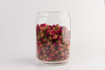 tea rose buds in the transparent jar isolated on white background