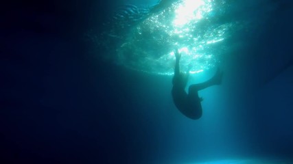Woman jumping into a floodlit pool at night - Powered by Adobe