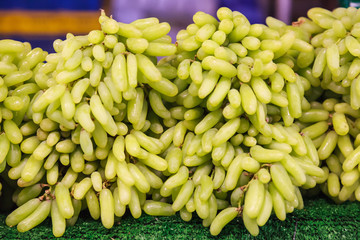 fresh natural wild tropical cluster of sweet Asian green raw ripe grapes berry fruit from garden on farmer market stall. Seasonal Food Nutrition, Summer grape fruit on street food market booth concept