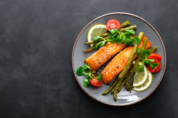 Grilled salmon fish steak, asparagus, tomato and corn salad on plate. Healthy dish for lunch. Top view