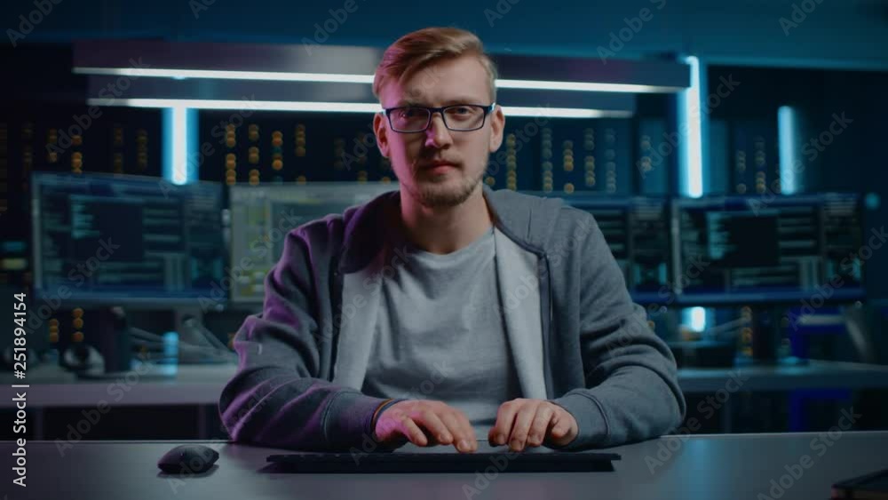 Poster Portrait of Software Developer / Hacker Wearing Glasses Sitting at His Desk and Working on Computer in Digital Identity Cyber Security Data Center. Hacking or Programming. POV Camera Shot