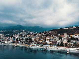 Fototapeta na wymiar Aerial panoramic view of Yalta city embankment with sea in cloudy weather, mountains and breakwaters, beautiful resort for vacation