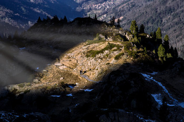 Two tourists walking on the touristic path lit by a beam of light in French Alps