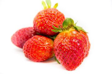 Several red strawberries with leaves on a white background