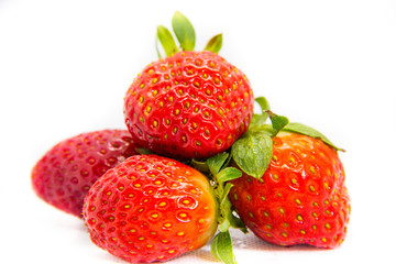 Several red strawberries with leaves on a white background