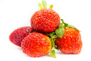 Several red strawberries with leaves on a white background