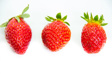 Several red strawberries with leaves on a white background