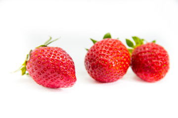Several red strawberries with leaves on a white background