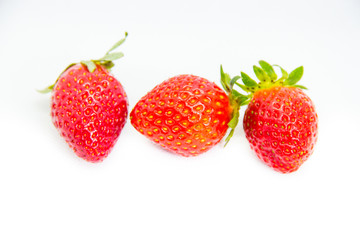 Several red strawberries with leaves on a white background
