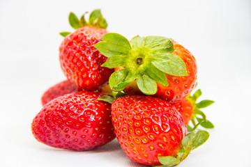 Several red strawberries with leaves on a white background
