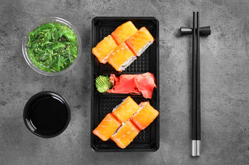 Tasty sushi rolls served on grey table, top view. Food delivery