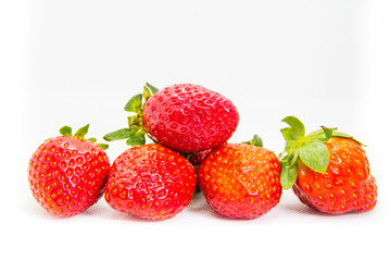 Several red strawberries with leaves on a white background
