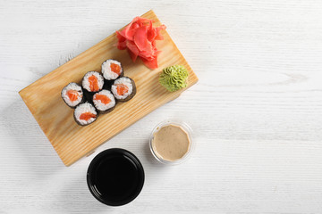 Obraz na płótnie Canvas Flat lay composition with sushi rolls and space for text on white wooden table. Food delivery