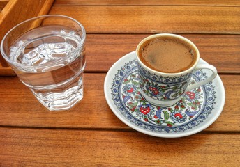 cup of coffee and a glass of water, asian style, beautifully painted handmade cup on a wooden table