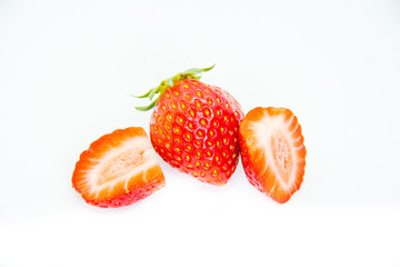 Whole and cut in half red strawberry and cut with leaves on white background