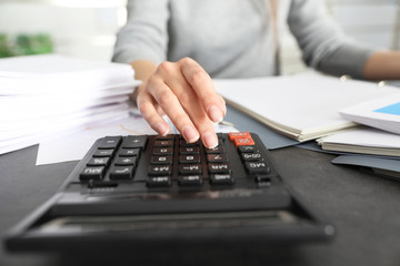 Office employee working with calculator and documents at table, closeup