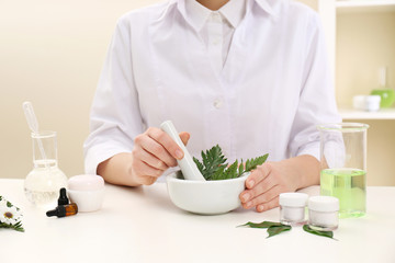 Female dermatologist creating skin care product at table, closeup