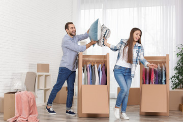 Young couple having pillow fight near wardrobe boxes at home