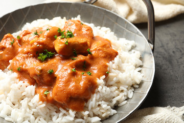 Delicious butter chicken with rice in dish and napkin on table