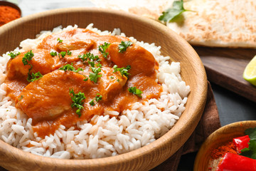 Bowl of butter chicken with rice on table