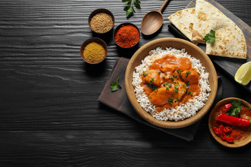 Delicious butter chicken with rice served on wooden table, flat lay. Space for text