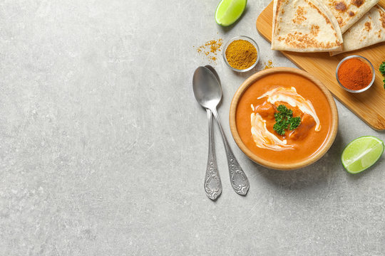 Delicious butter chicken served on grey table, top view with space for text. Traditional indian Murgh Makhani
