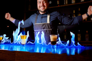 Fiery show at the bar. The bartender makes hot alcoholic cocktail and ignites bar. Bartender prepares a fiery cocktail. Fire on bar.